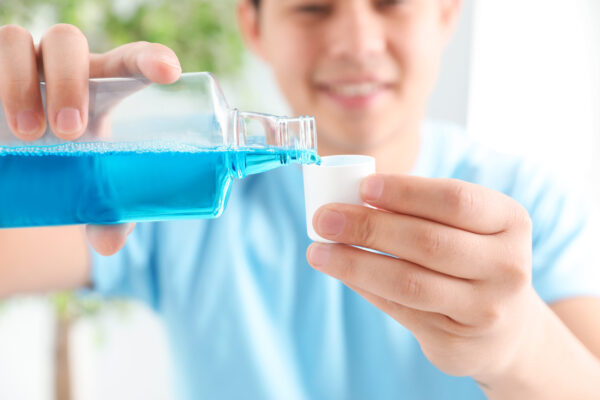 Man Pouring Mouthwash From Bottle Into Cap, Closeup. Teeth Care