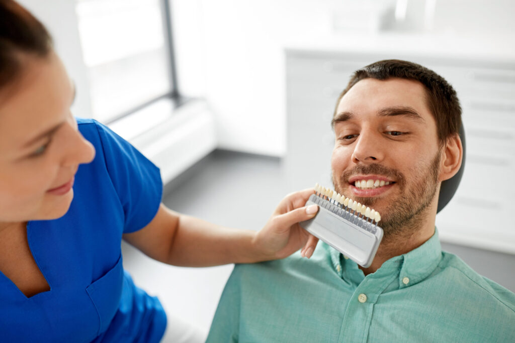 Dentist Choosing Tooth Color For Patient At Clinic